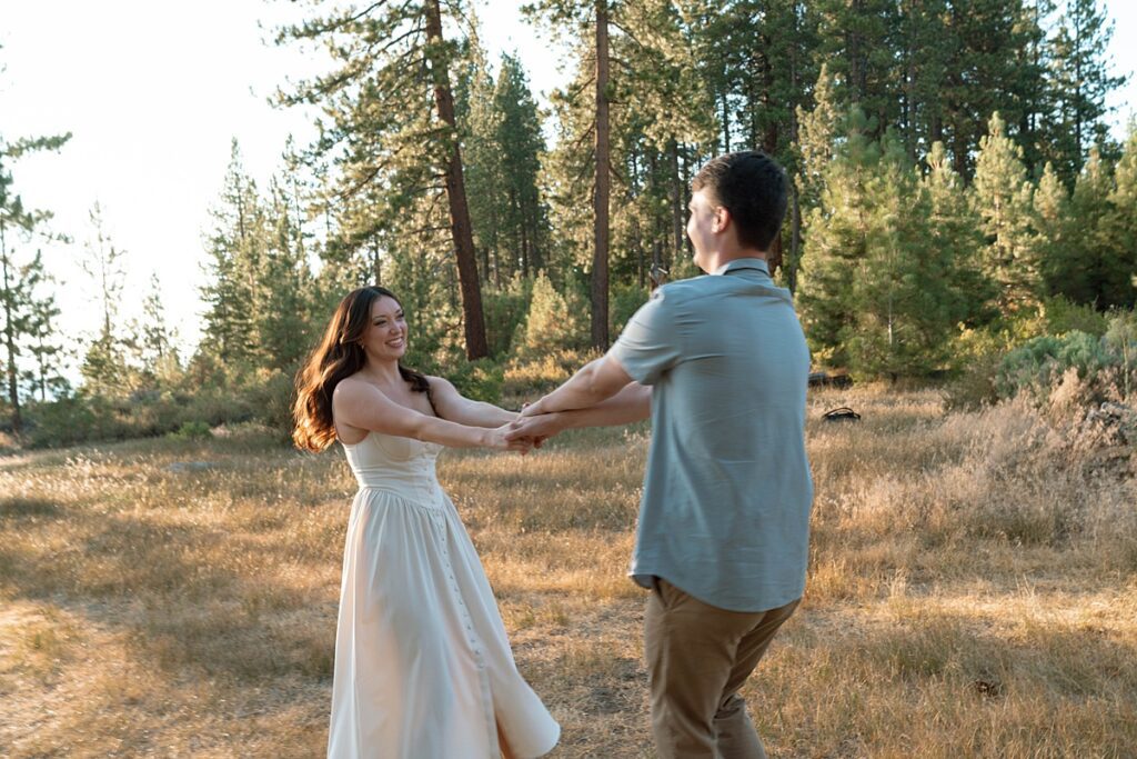 photographer captures engaged couple spinning in zephyr cove meadow 
