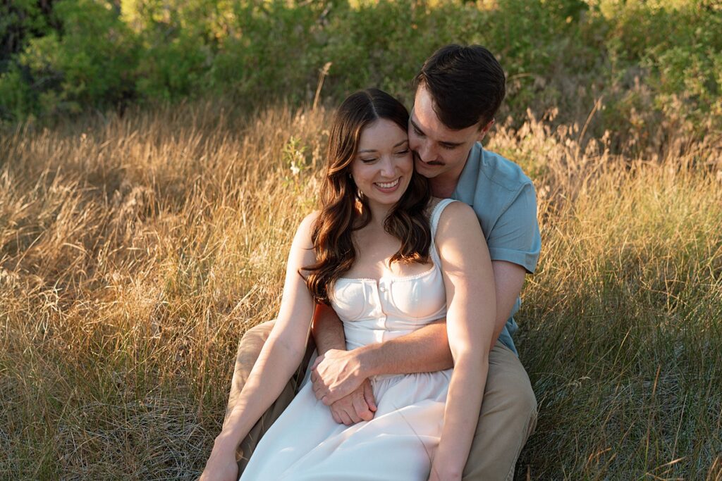 engaged couple embraces in the grass of a zephyr cove meadow 