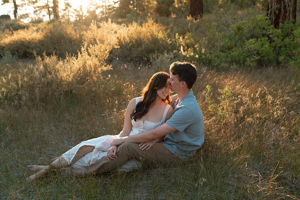 engaged couple embraces in the grass of a zephyr cove meadow captured by lake tahoe photographer