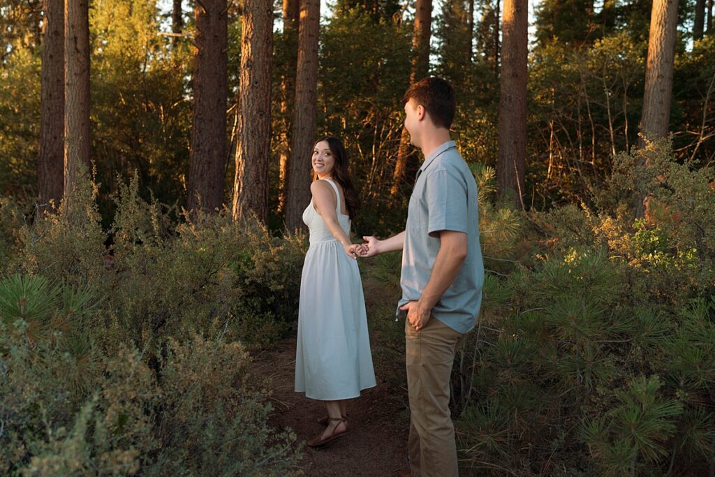 woman leading her fiance through the woods captured by lake tahoe wedding photographer 