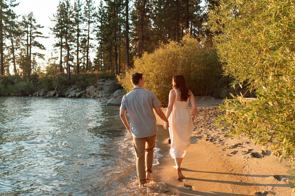 engaged couple walking on the beach during golden hour captured by lake tahoe wedding photographer 