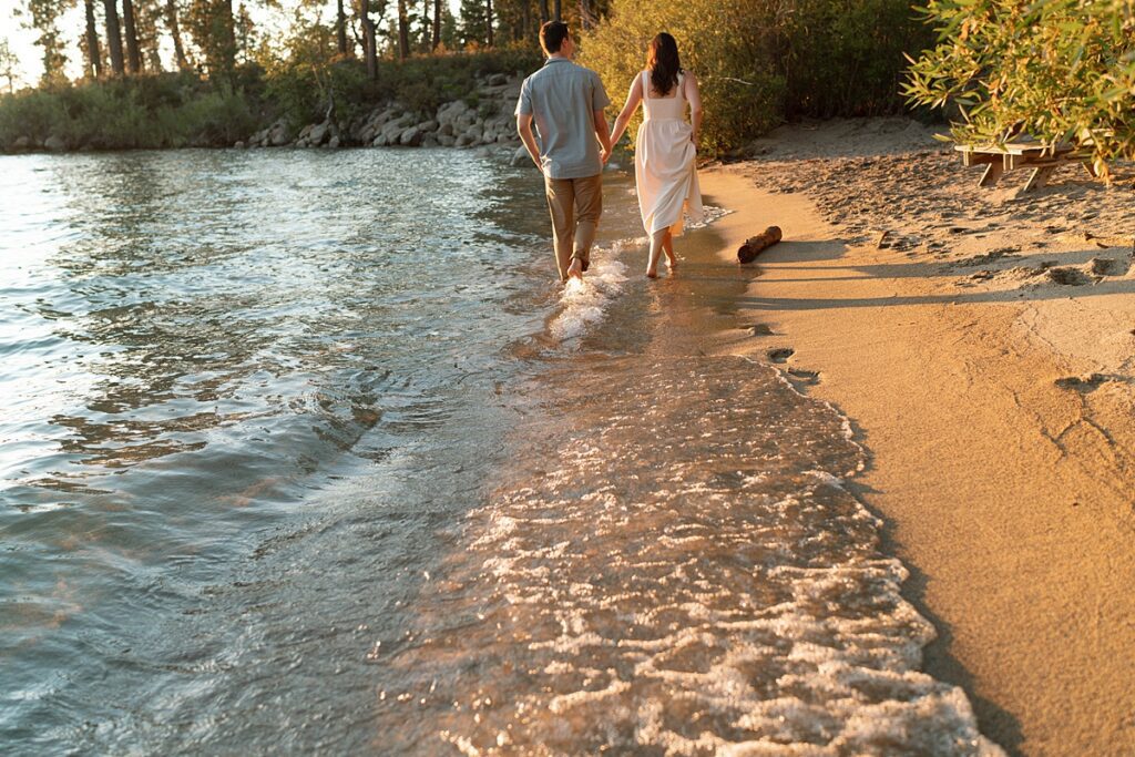 engaged couple walking on the beach during golden hour captured by lake tahoe wedding photographer 