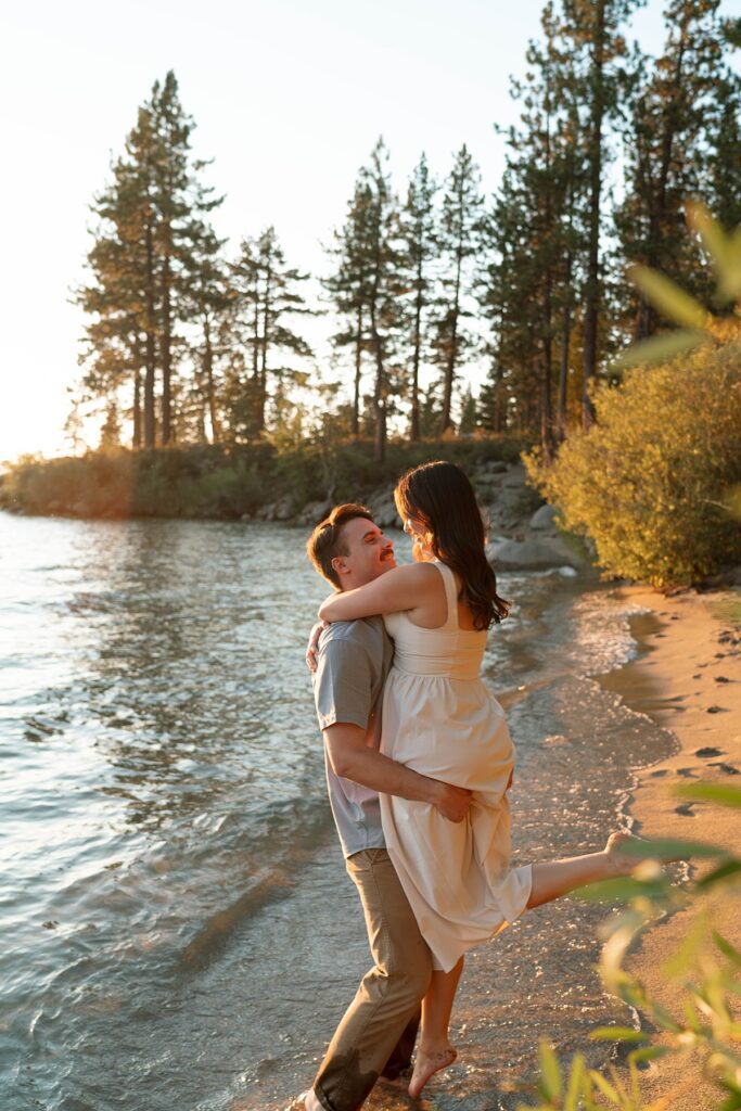 couple lifts and spins on a beach in lake tahoe during their engagement session