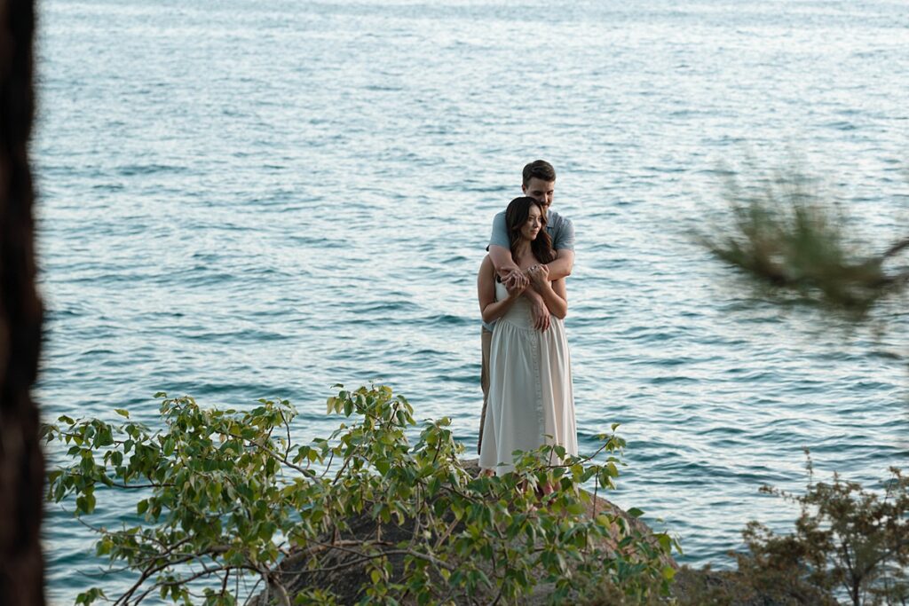 engaged couple embracing in front of lake tahoe at zephyr cove 